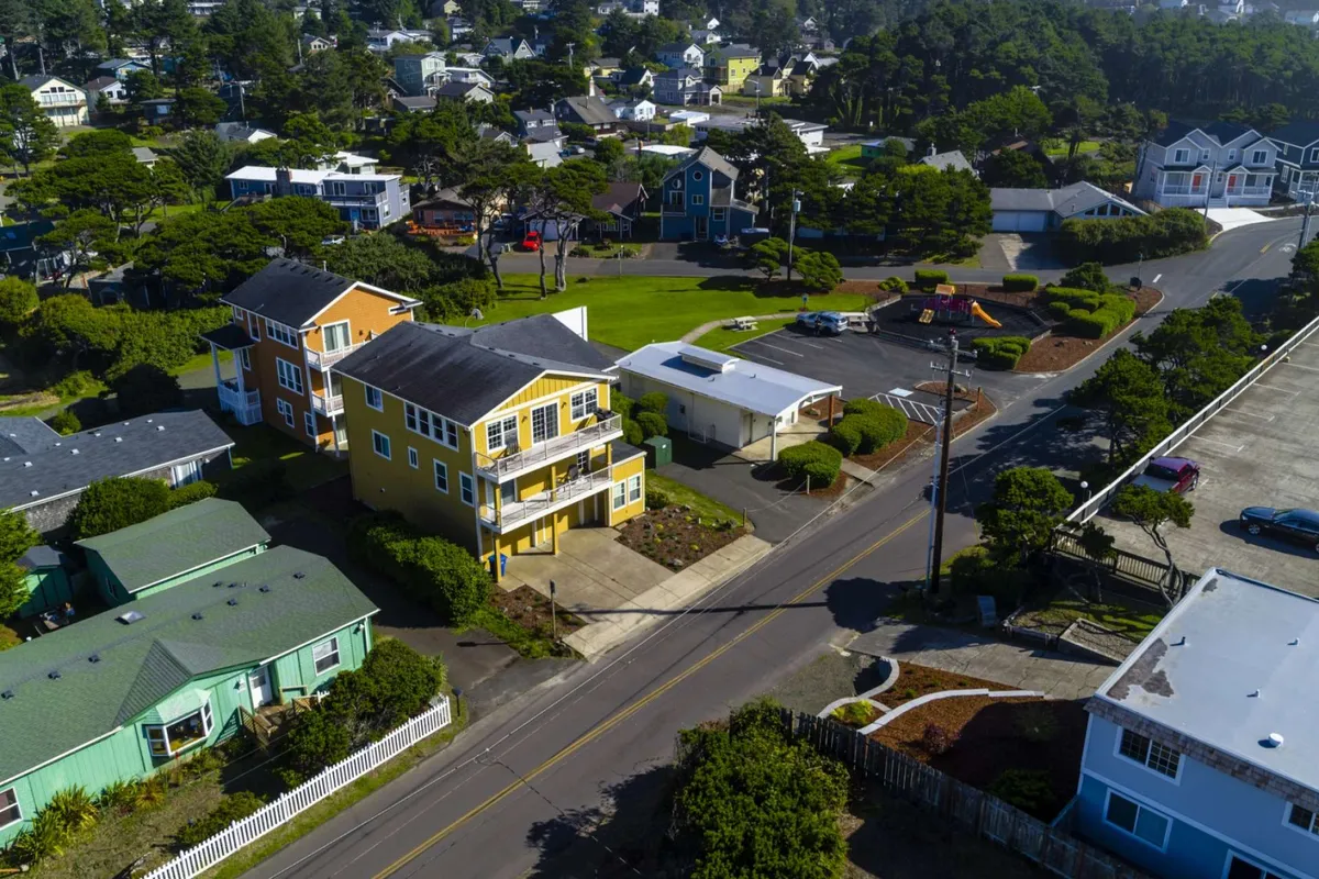 A row of cheerful, colorful houses faces onto green lawns and neatly trimmed bushes, with clear evidence of outdoor activities and spaces for family gatherings and community events. The warm, inviting atmosphere evokes a sense of neighborhood unity and safe, welcoming streets.