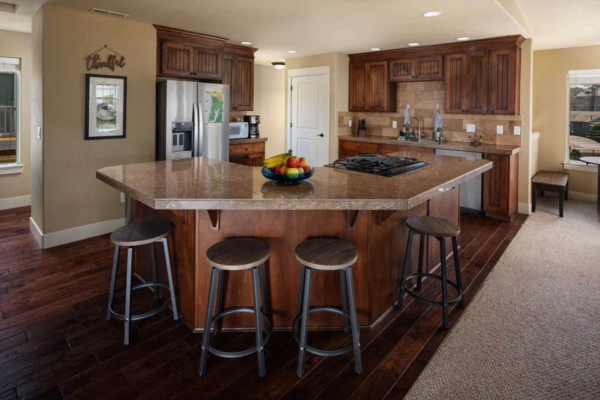 A warm, welcoming kitchen with a central island, wooden cabinetry, and stools, designed for gathering and family bonding. The inviting space suggests both lively meals and relaxed conversations, providing a cozy haven after outdoor fun.