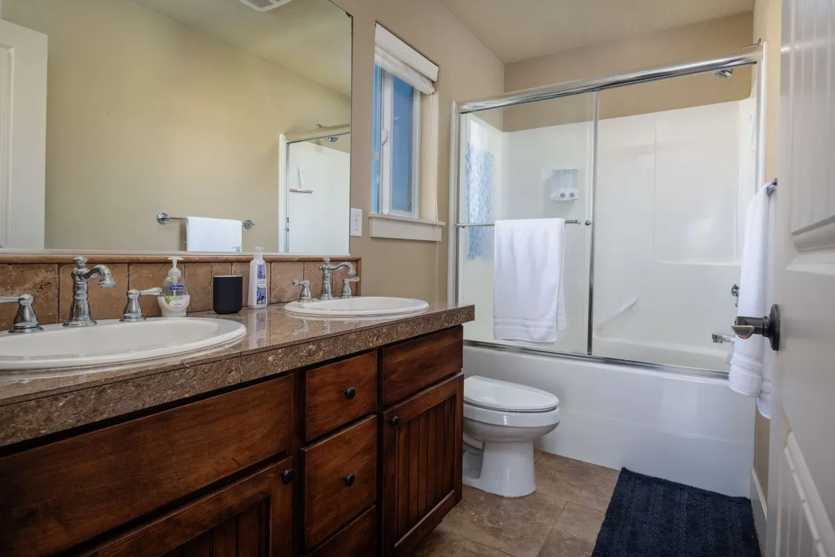 A bright, functional bathroom with double sinks, large mirrors, a spacious shower area, and neatly arranged towels. Ample counter space and storage make morning and evening routines easy for families.
