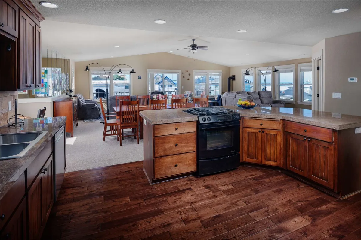 An open-concept living space featuring a kitchen island, a spacious dining table set for a group, and large windows that bathe the area in natural light. The space blends the kitchen and dining zones, evoking a sense of togetherness and warmth.